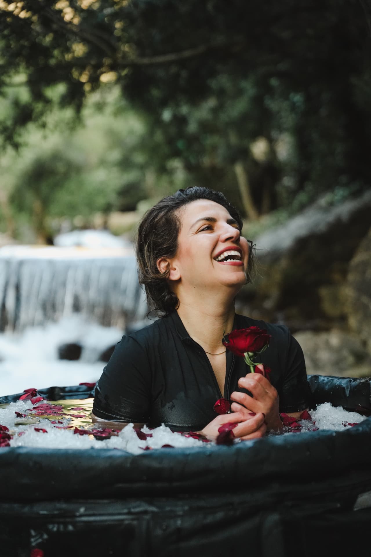 Zainab laughing in an ice bath while holding a red rose